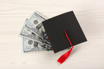 Scholarship concept. Graduation cap and banknotes on white wooden table, above view
