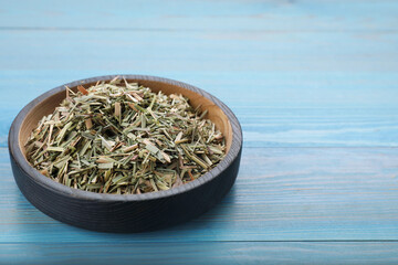 Bowl with aromatic dried lemongrass on light blue wooden table, closeup. Space for text