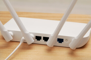 New white Wi-Fi router on wooden table, closeup