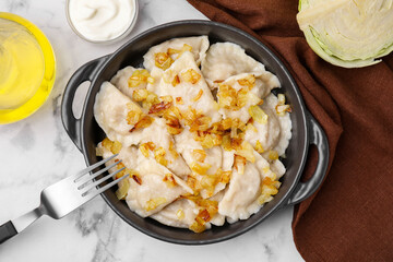 Cooked dumplings (varenyky) with tasty filling and fried onions on white marble table, flat lay