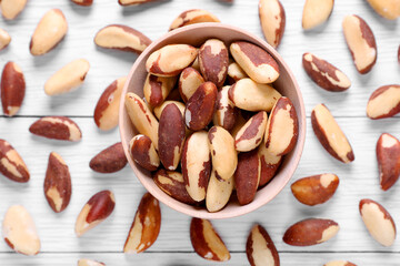 Delicious Brazil nuts on white wooden table, flat lay