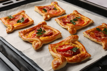 Fresh delicious puff pastry with tasty filling on baking sheet, closeup
