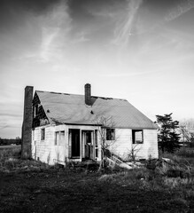Black and white image of a derelict building with an overgrown law