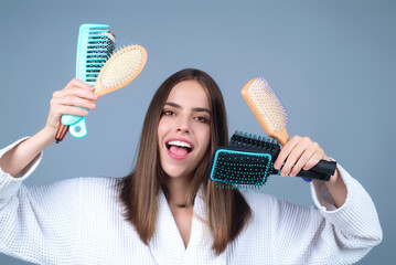 Beautiful model girl with comb brushing hair. Beauty woman with straight hair on studio background....