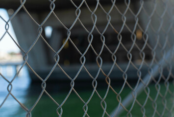Chain link fence in front of a body of water, under a bridge in Adelaide, South Australia, outer harbor