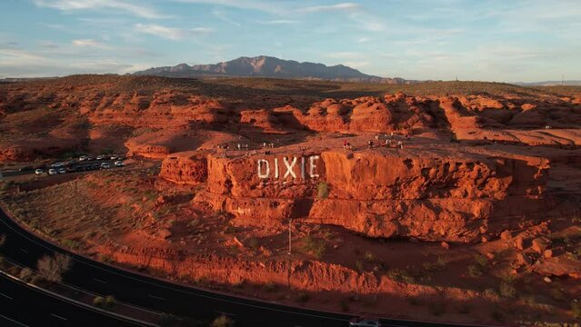 Aerial View of Dixie Rock, St. George Utah USA, People on Tourist Attraction and Traffic on Red Hills Parkway at Sunset, Revealing Drone Shot