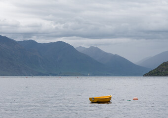 Fototapeta na wymiar Isolated yellow row boat on Lake Wakatipu, amongst the mountains outside of Queenstown New Zealand