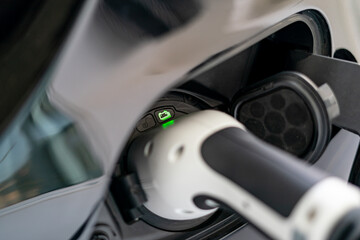 Plugged cable charging an electric car at home.