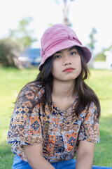 Depressed young woman looking at camera sitting in the park. Outdoor portrait of a sad teenage girl looking thoughtful about troubles. Lonely sad woman deep in thoughts with soft focus.