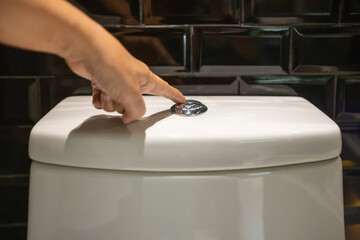 Senior woman hand push flushing toilet