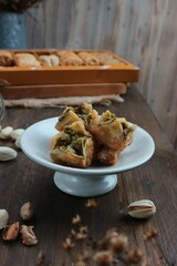 sweet pastries filled with nuts with pistachios scattered on a wooden table