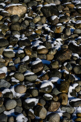 Textures in nature, snow covered river rocks on a sunny winter day, as a nature background
