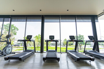 Fototapeta na wymiar Treadmills set in gym interior. Fitness club with equipment. Sports background with glass windows
