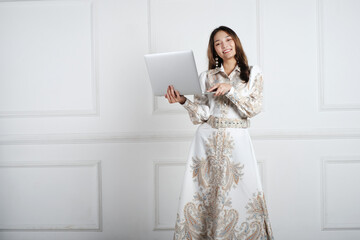 A young girl wearing a floral dress and holding a laptop. Online shopping concept.