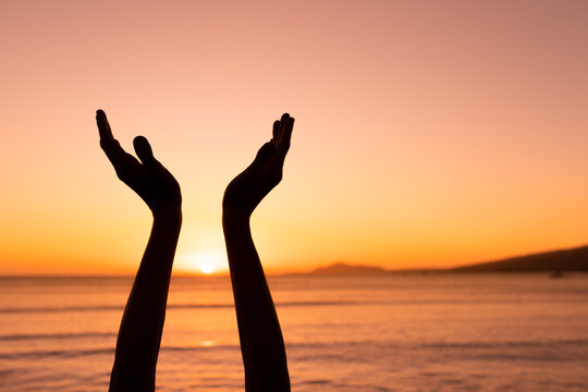 silhouette of a person with hands up to sunset at dawn 