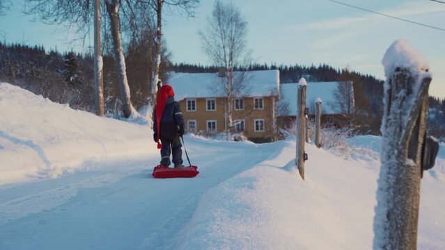 A little boy pulls a sleigh on a Christmas day in winter in Norway