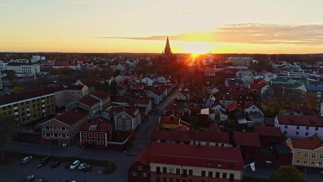 The city of V&auml;stervik in Sweden. Architecture of houses with red roofs and silhouette of a church in the distance. Panorama of a peaceful city with the horizon of the setting sun. Aerial view.