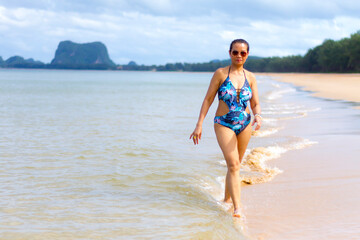 Fototapeta premium Woman with swimsuit walk happy on water at beach