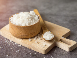 sea crystal salt in a wooden bowl and spoon on a wooden board