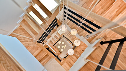Drop lighting is installed from the ceiling of the stairway that bends in a Klitschko shape to the first floor