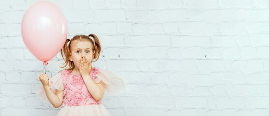 banner excited surprise emotion child girl in festive dress hold pink baloon isolated wall background. Happy birthday party, shopping sale gift presents children holiday