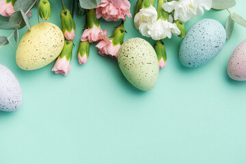 Easter colored eggs and a bouquet of white and pink carnations with eucalyptus branches on a soft...