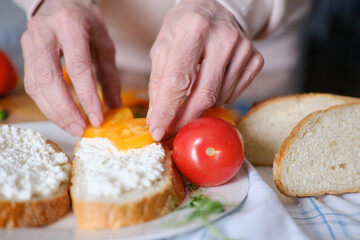 Age woman preparing healthy sandwiches with microgreens and vegetables