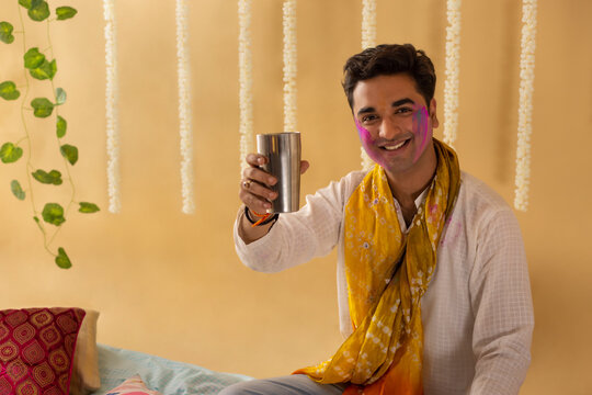 A young man  drinking a glass of bhang on holi festival