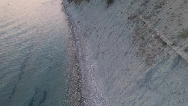 Aerial tilt-up shot showing the sea and sandy cliffside with medicinal mud coast of Arillas, Corfu, Greece,