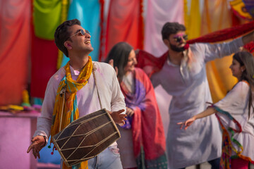 A group of young men and women happily dancing together while celebrating holi