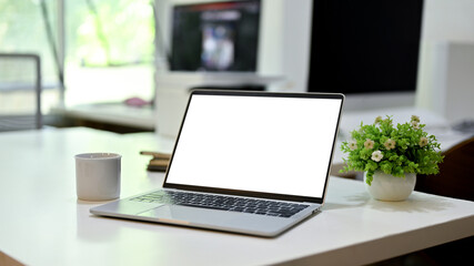 Laptop white screen mockup is on a modern office desk. close-up image