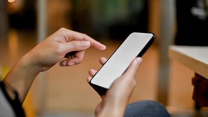 Close-up image of a woman's hand holding a smartphone, finger touching on screen