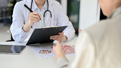 Female doctor meeting with her patient in the office, checking up and discussing treatment plans.