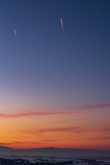 planes in the colorful sky after sunset, in the mountains - obrazy, fototapety, plakaty