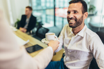 Hand giving coffee to cheerful businessman