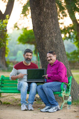 Indian man showing laptop screen at park