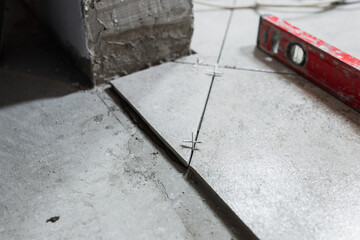 Laying ceramic tiles on the floor according to the level - a professional tiler performs the interior decoration of the room