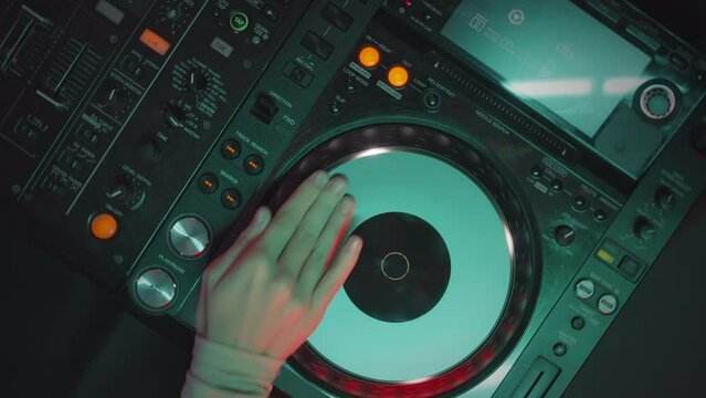 Top view of unrecognizable female dj spinning record on turntable while playing music at party in night club