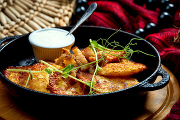 Traditional Ukrainian deruny with sour cream in a black pan. Ukrainian cuisine Potato pancake. Close up