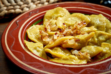 Traditional Ukrainian varenyky stuffed with meat and fried onions in clay dishes. Ukrainian cuisine. Close up