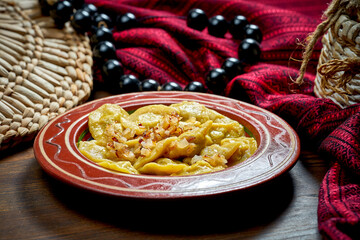 Traditional Ukrainian varenyky stuffed with meat and fried onions in clay dishes. Ukrainian cuisine. Close up