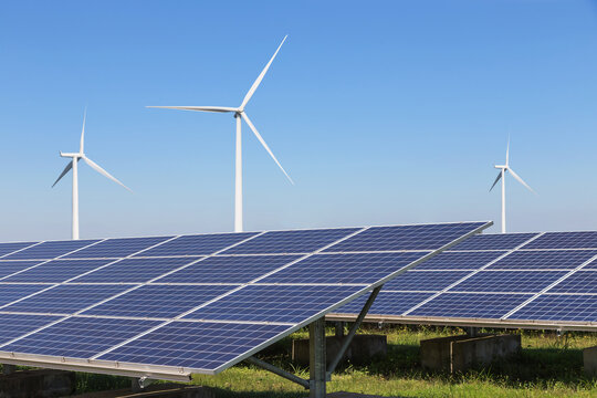solar cells with wind turbines generating electricity in hybrid power plant systems station on blue sky background 