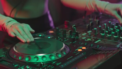 Cropped shot of unrecognizable female dj hands creating and regulating music on mixing console at night club party