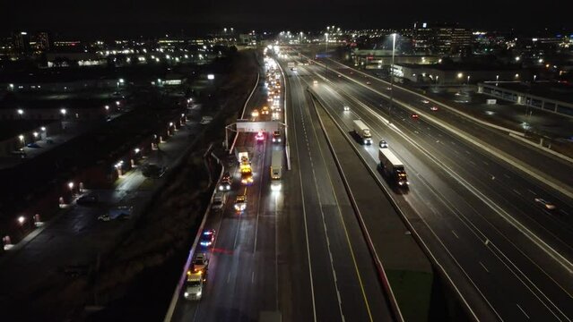 Emergency vehicles with flashing lights on highway accident scene at night, aerial view