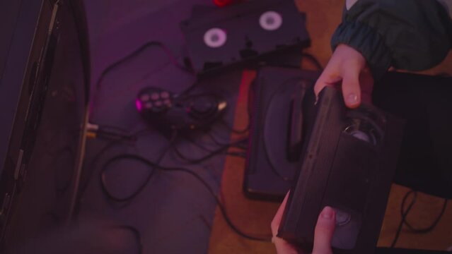 Top view of unrecognizable female hand taking cassette out of retro VHS player
