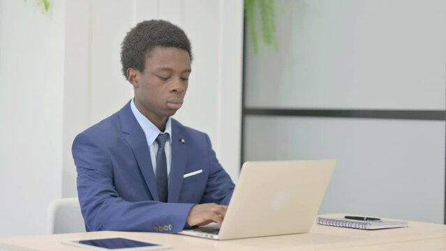 African Businessman Typing on Laptop in Office