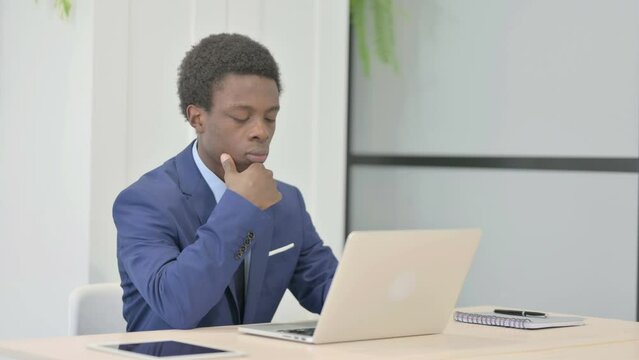 African Businessman Thinking while Working on Laptop