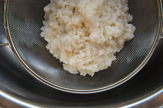 rice cooked in a grey metal sieve