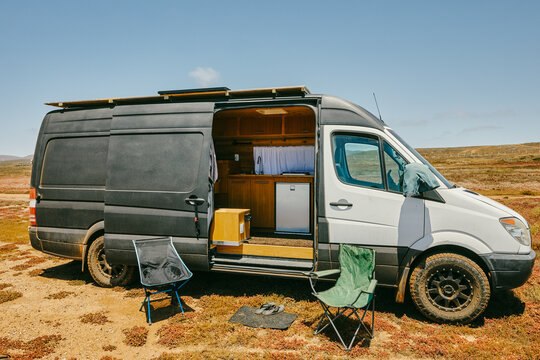 Camper van parked with doors open on isolated beach in Baja, Mexico.