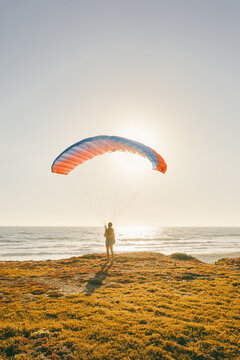 Young man paragliding during sunset over cliffs in Baja, Mexico.